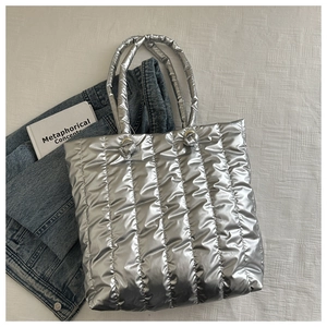 Close-up of silver quilted puffer tote bag with metallic finish and padded handles