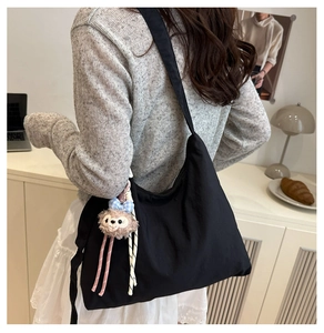 Détail d'un grand sac cabas en nylon noir mat avec bandoulière et porte-clés