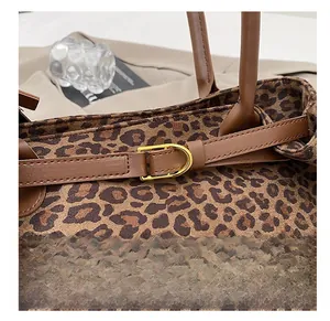 Detail of leopard print tote featuring brown leather straps and gold horseshoe buckles