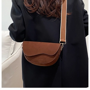Detail of dark brown matte leather saddle bag with wave-cut flap and wide strap