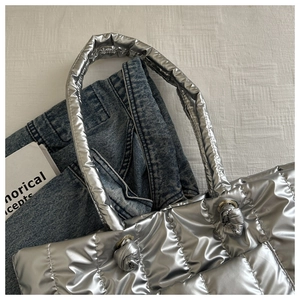 Detail of silver quilted padded tote bag with metallic finish and knot handle design
