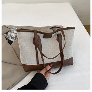 Detail of canvas tote bag with brown leather trim and sturdy shoulder straps