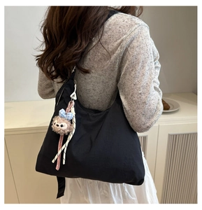 Détail d'un sac cabas en nylon noir avec un charmant pendentif en peluche attaché