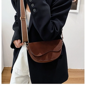 Detail of brown saddle bag with unique wavy flap and adjustable wide shoulder strap
