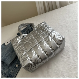 Close-up of silver quilted tote bag with metallic finish and padded cotton handles