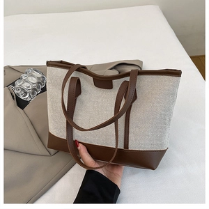 Detailed view of cream canvas and dark brown faux leather patchwork tote bag with long handles