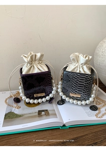 Detail of faux snake skin texture and pearl handle on drawstring bucket handbags