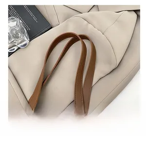 Detail view of the deep brown leather handle with premium stitching on a minimalist tote bag