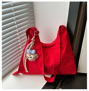 Détail du sac bandoulière en nylon rouge avec sangle large et pendentif peluche
