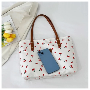 Detailed view of canvas tote bag with cherry print and leather straps with phone for scale
