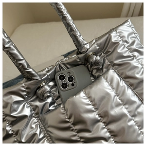 Detail of silver quilted tote bag showing exterior pocket and spacious padded interior