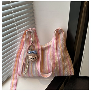 Détail du sac fourre-tout à rayures gaufrées avec pendentif peluche et nœud décoratif
