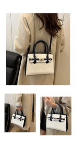 Dettaglio della borsa in pelle bianca a grana litchi con manici blu e chiusura dorata
