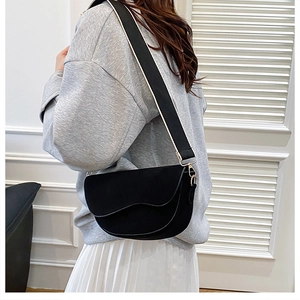 Detail of a matte black saddle bag with a wide black and white patterned shoulder strap