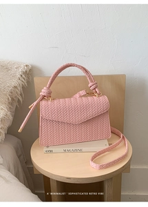 Detail of pink woven handbag featuring herringbone pattern, knotted handle and gold metal clasp