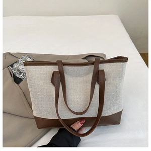Detail of contrast stitching on canvas tote bag with premium brown leather handles