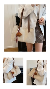 Detail of beige canvas tote with brown leather handles and a plush bear pendant