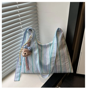 Détail du sac fourre-tout en seersucker à rayures bleu-violet avec breloque singe
