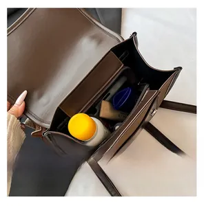 Detail view of the spacious inner compartments and zip pockets of the brown shoulder bag