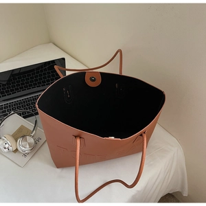 Dettaglio della borsa tote in ecopelle marrone con testo in rilievo e chiusura magnetica
