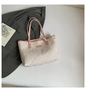 Detail of quilted tote bag featuring embossed cream texture and pink leather handles