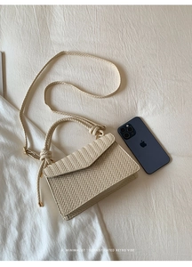 Close-up of cream woven handbag texture with knotted shoulder strap and gold hardware