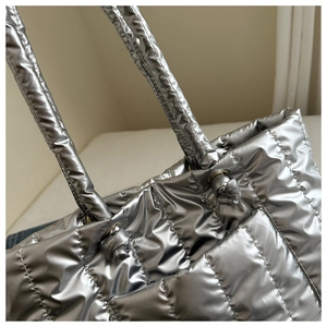 Close-up of a silver quilted tote bag with metallic finish and knotted handle detail