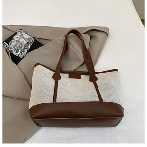 Close-up of contrast stitching and brown leather trim on white canvas tote bag