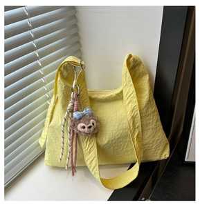 Détail du sac cabas jaune plissé en toile avec un charm ours en peluche brun et nœud bleu