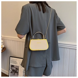 Detail of beige structured box handbag with gold metal frame and elegant chain strap