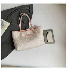 Detailed top view of a white quilted tote bag with pink handles and fashion accessories