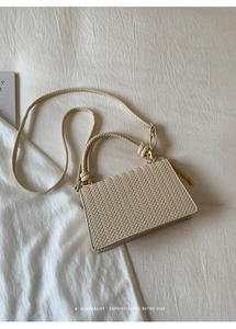 Detailed macro view of cream woven leather texture and elegant gold metal buckle on bag