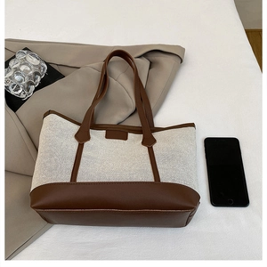 Detail of premium woven tote bag with brown leather trim and contrast stitching