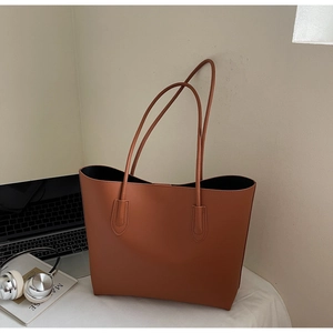 Borsa tote in pelle marrone caramello con laptop e cuffie sulla scrivania