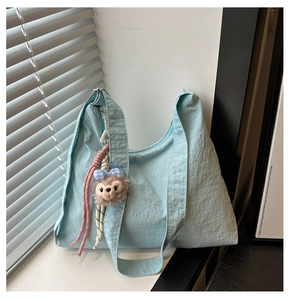 Détail d'un sac hobo bleu en nylon avec charm en peluche et texture de tissu plissé