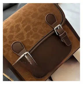 Detail of vintage messenger bag featuring brown faux leather texture and silver buckles