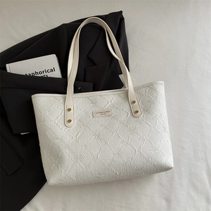 Chic white textured tote bag with gold hardware on gray background with professional accessories