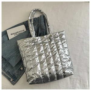 Detail of silver metallic puffer tote bag with vertical quilting and top handles