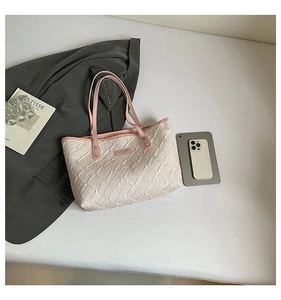 Detail of quilted beige tote bag fabric with pink strap and metallic rivet hardware