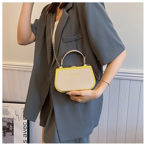 Detail of trendy box handbag in cream and yellow with gold handle and chain strap