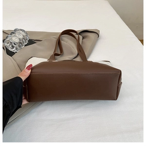 Detail of the stitched bottom and brown leather trim on the beige canvas tote bag
