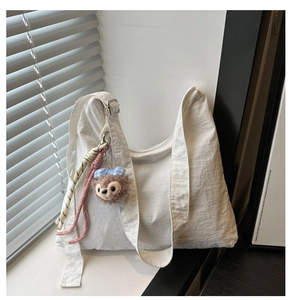 Détail du sac fourre-tout blanc cassé avec breloque en peluche et cordon tissé coloré