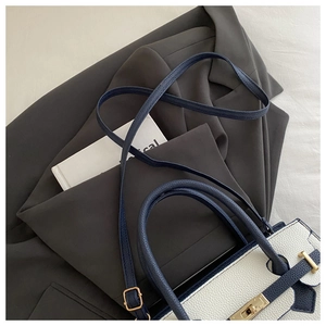 Dettaglio pelle bianca litchi con finiture blu navy e chiusura girevole dorata