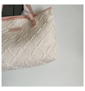 Detail of quilted fabric texture and pink leather brand tag with golden metal rivets