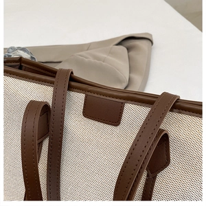 Detailed close-up of premium canvas tote bag with brown leather handles and stitching