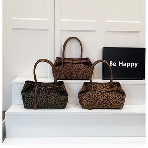 Detailed view of leopard print tote bags in three colors arranged on white steps