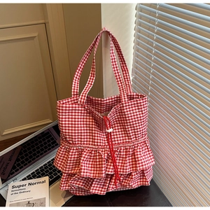 Detail of red gingham canvas tote bag featuring stylish ruffled base and drawstring closure