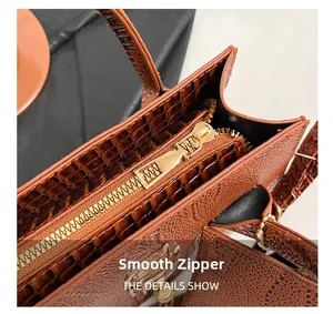 Détail de la fermeture éclair dorée lisse et du motif crocodile sur sac à main brun