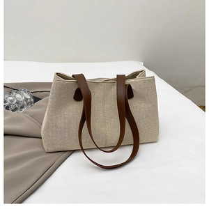 Dettaglio di una borsa tote in tela beige con trama intrecciata e manici in pelle marrone