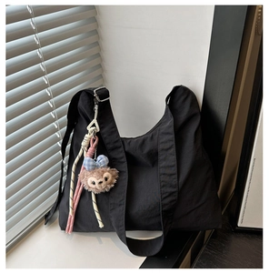 Détail du sac cabas en toile noire avec bandoulière et pendentif en peluche